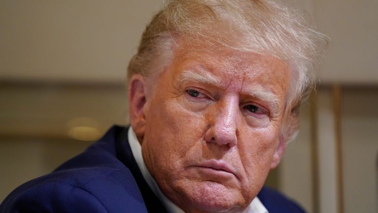 Former President Donald Trump listens as he speaks with reporters...