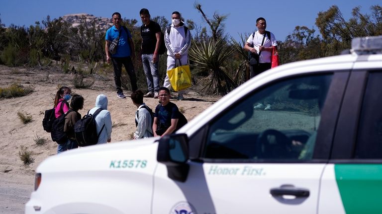 Asylum-seekers wait in a makeshift camp after crossing the nearby...