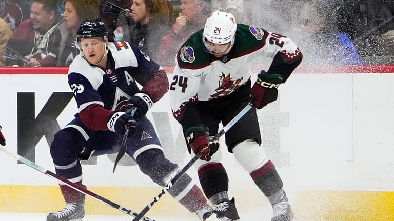Colorado Avalanche center Nathan MacKinnon, left, fights for control of...