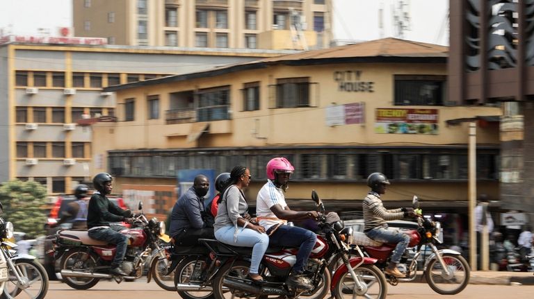 Drivers of motorcycle taxis, known locally as boda-bodas, ride with...