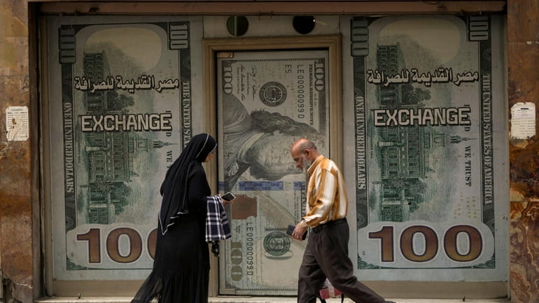 Egyptians walk past an exchange office in Cairo, Egypt, Wednesday,...