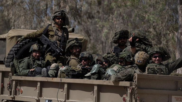 Israeli soldiers move on the back of a truck near...