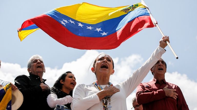 Opposition leader Maria Corina Machado waves a Venezuelan national flag...