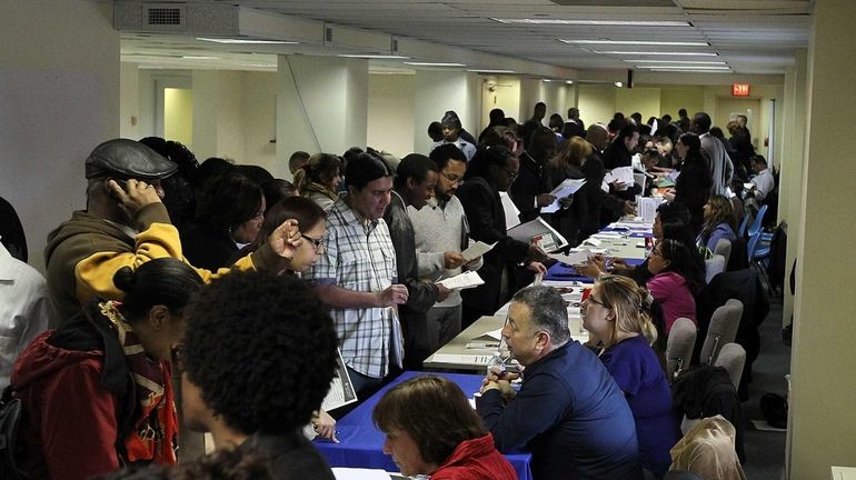 Job seekers meet with recruiters during a job fair this...