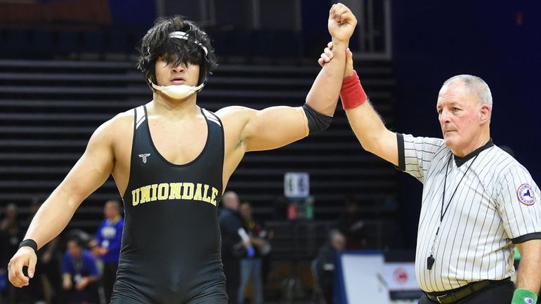 Luis Lizama of Uniondale raises his arm after pinning Aidan...