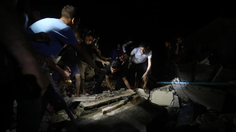 Palestinians search for survivors after an Israeli airstrike on a...