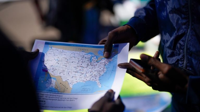 Migrants study a map of the United States at Friday,...