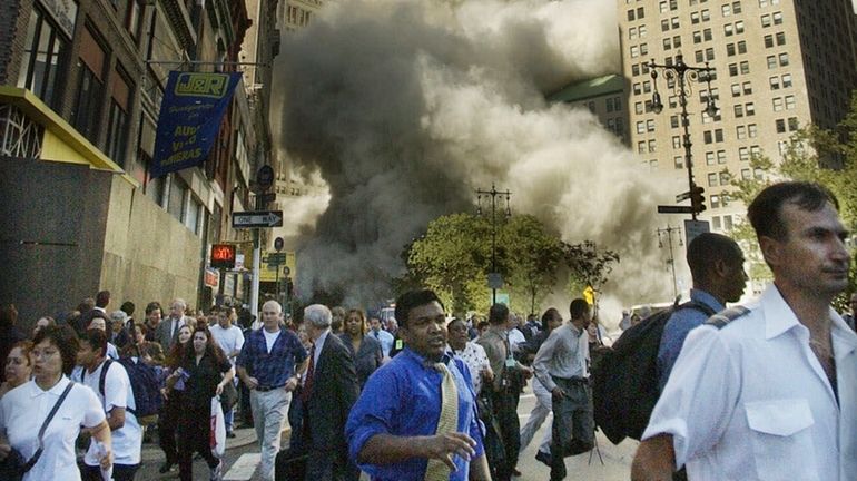 Dust clouds chase people fleeing the World Trade Center as the...