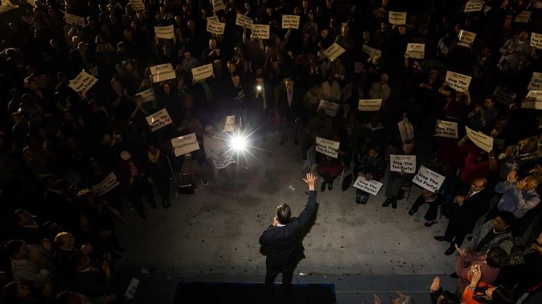 Tom Suozzi addressing the crowd of a few hundred as...