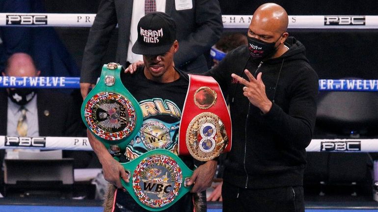 Errol Spence Jr., poses by trainer Derrick James after defeating...