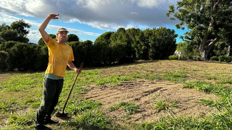 Chris Cole raises an arm to show how high invasive...