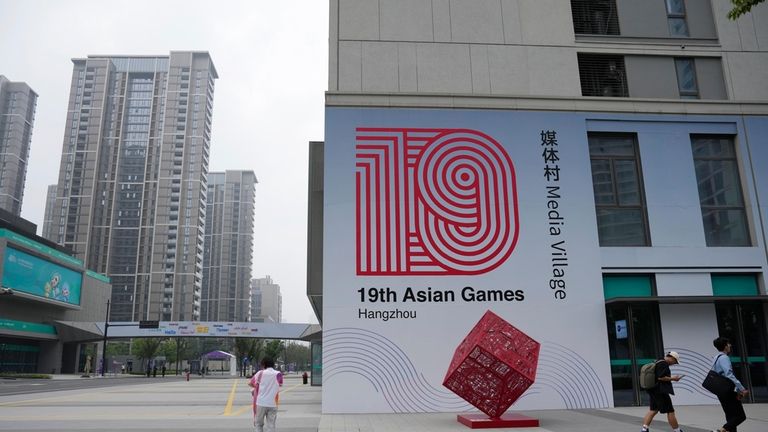 People walk inside the media village at the 19th Asian...