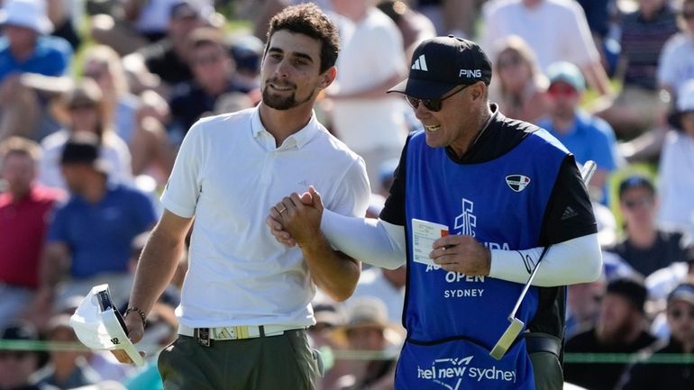 Chile's Joaquin Niemann, left, is congratulated by his caddie after...