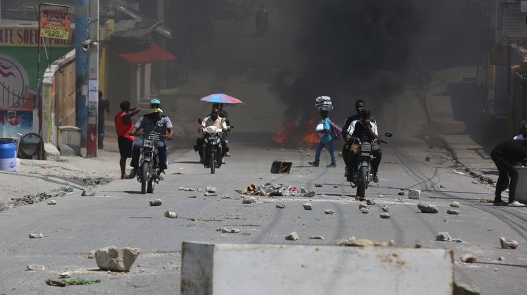 A street is blocked with burning tires and obstacles placed...