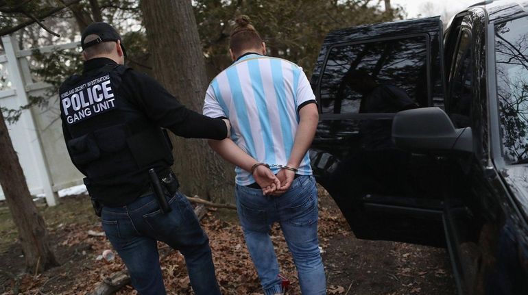 Federal agents detain a suspected MS-13 gang member on March...