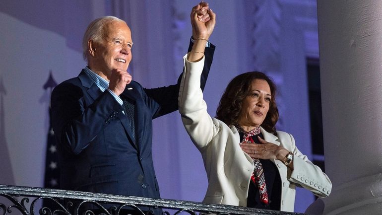 President Joe Biden raises the hand of Vice President Kamala...