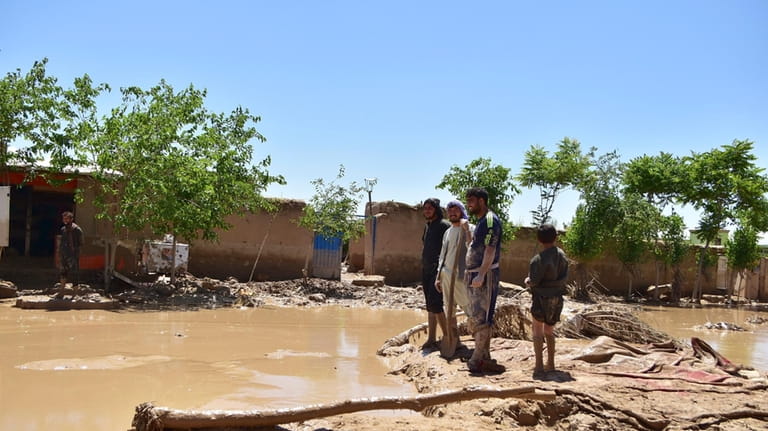 People stand near damaged homes after heavy flooding in Baghlan...