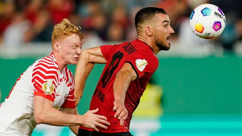 Leipzig's Nicolas Seiwald, left, and Wiesbaden's Ivan Prtajin, right, challenge...