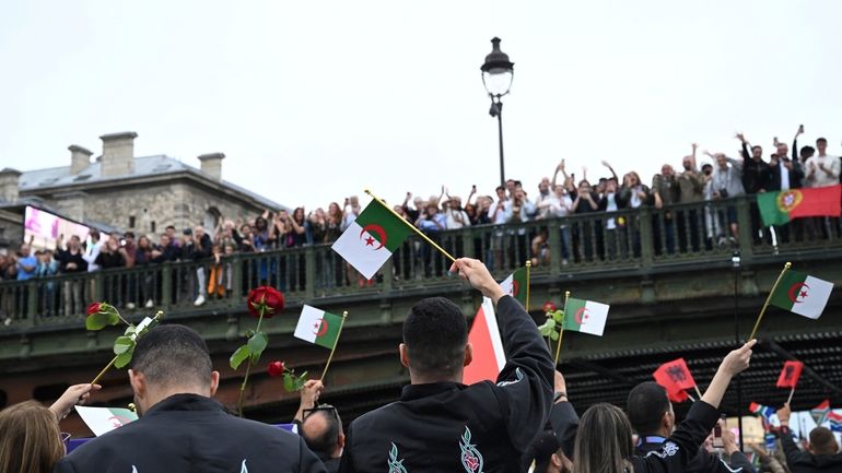 Athletes from Algeria wave flags aboard a boat on the...