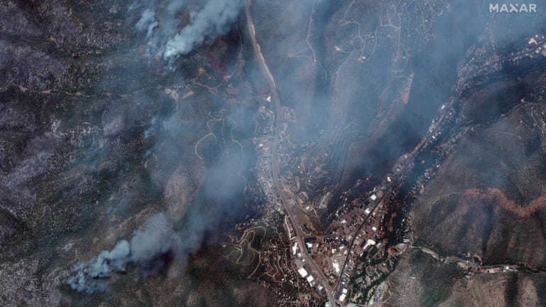 This satellite image released by Maxar Technologies shows wildfires burning...