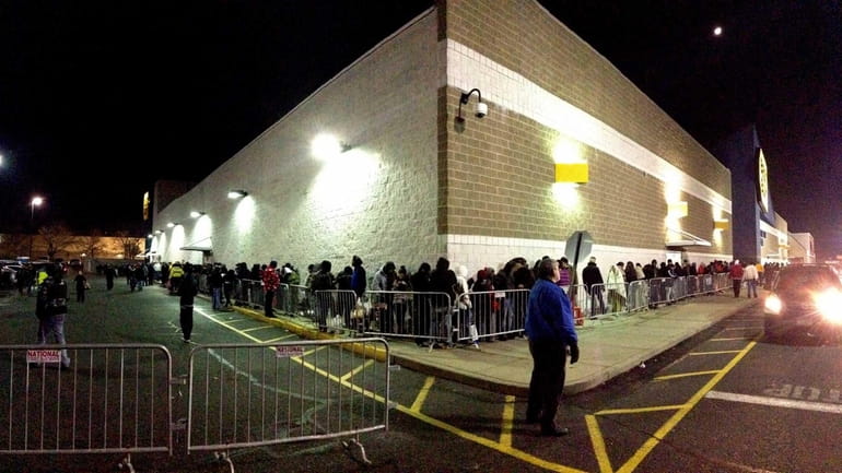 Hopeful buyers wait in a line outside Best Buy at...