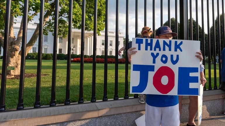 Hugh Kieve, 10, from Washington, holds a sign in front...