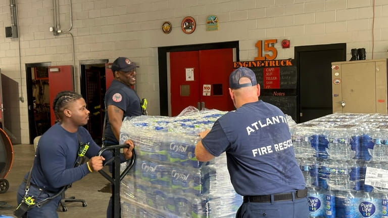 Atlanta firefighters unload bottled water to distribute to residents at...