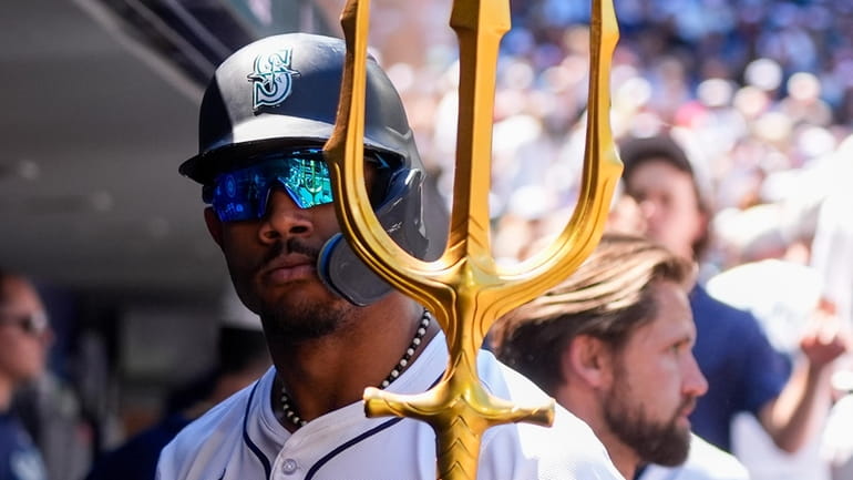 Seattle Mariners' Julio Rodríguez holds a trident in the dugout...