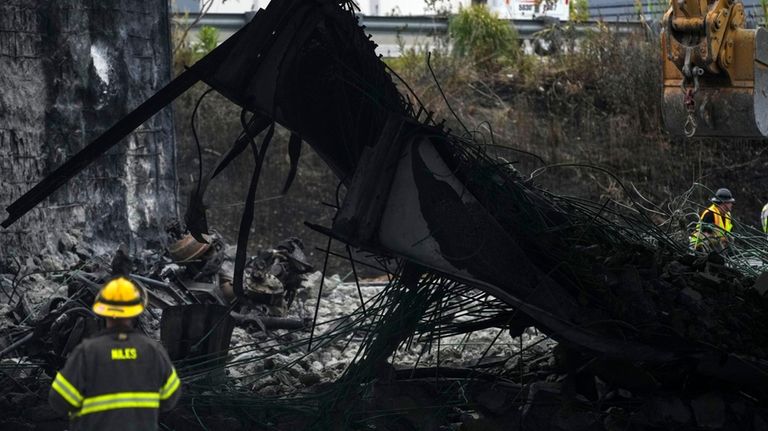 A firefighter views the aftermath of an elevated section of...