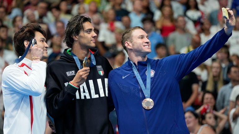 Gold medalist Thomas Ceccon, of Italy, stands on the podium...