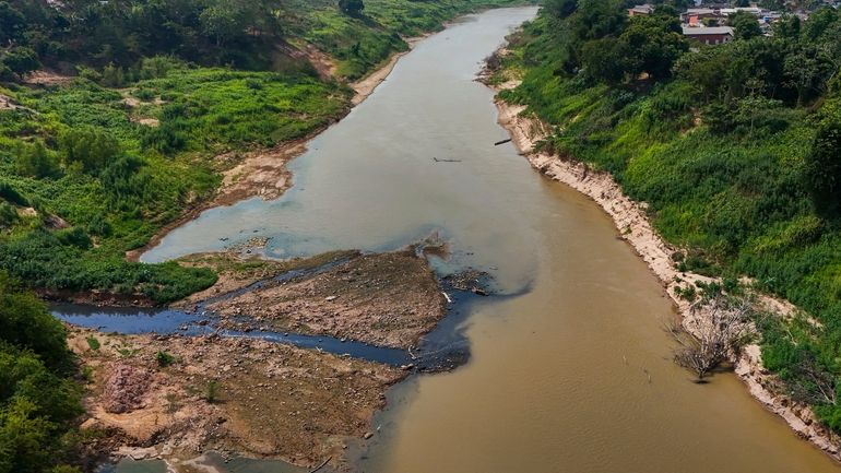 Blackwater, left, pollutes the Acre River near Rio Branco, Acre...