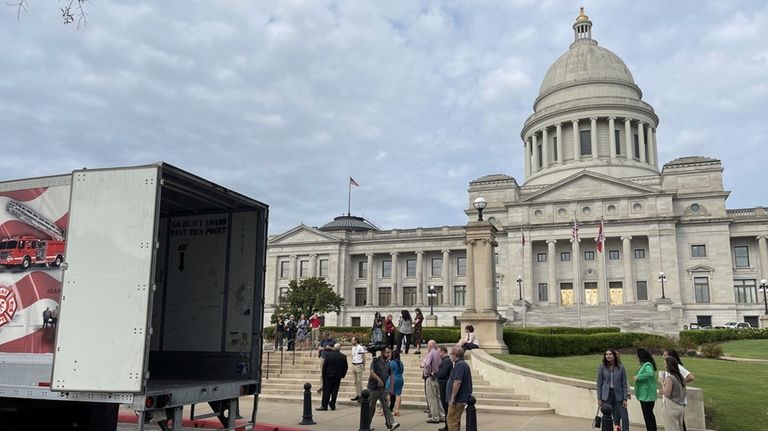 A crowd gathers to watch a tractor trailer holding a...