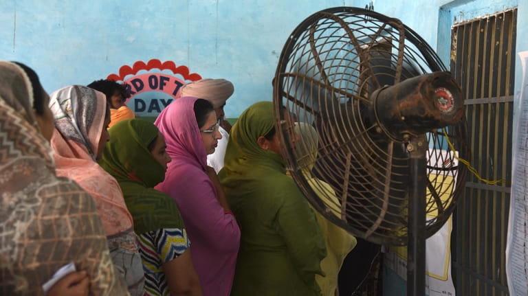 Women wait in a queue to cast their vote standing...
