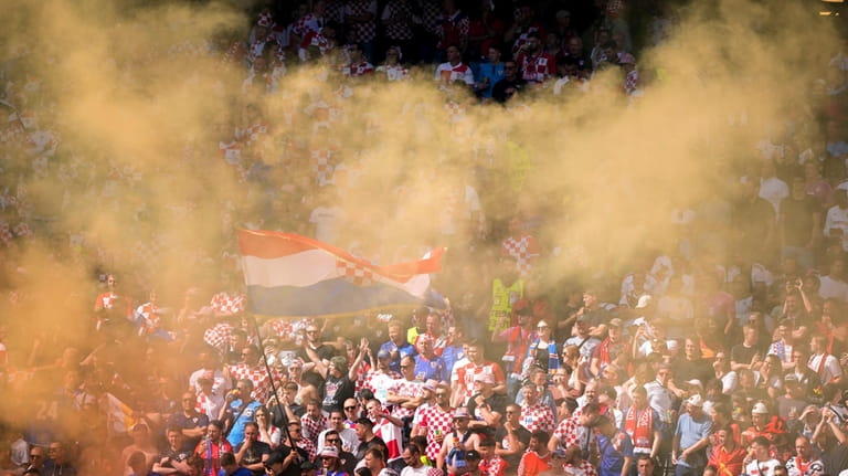 Croatian supporters light a flare as they cheer during a...