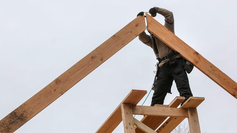 Carpenters frame a roof on a new home under construction...