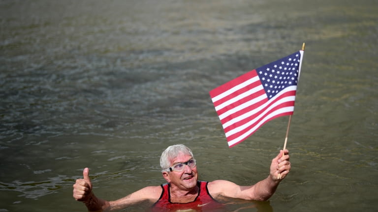 Joel Stratte-McClure, 75, of the US, holds American flag after...