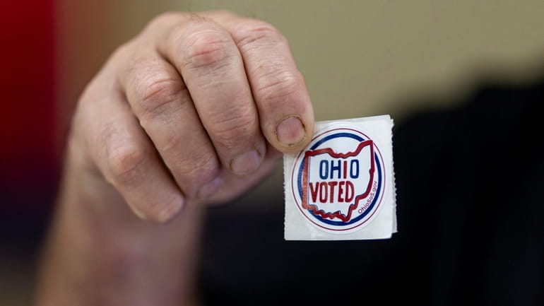 Voters grab "Ohio Voted" stickers after filling out ballots on...