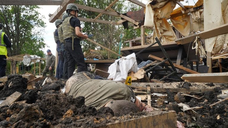 Police officers inspect the site of the Russian missile attack,...