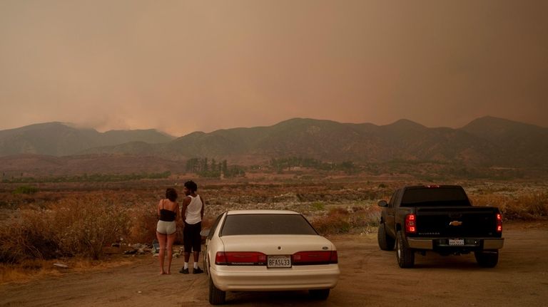 People watch as the Line Fire advances in Mentone, Calif.,...