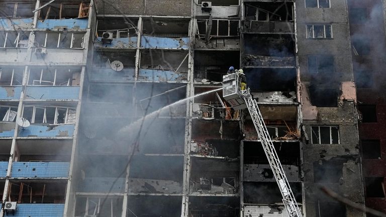 Firefighters work to extinguish a fire in an apartment building...