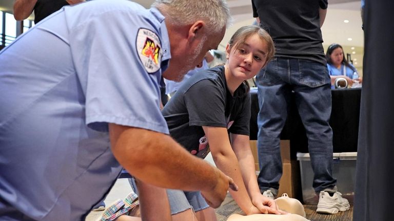 Nesconset EMT Kenneth Walsh instructs 10-year-old Eva Raiescu, of Nesconset,...