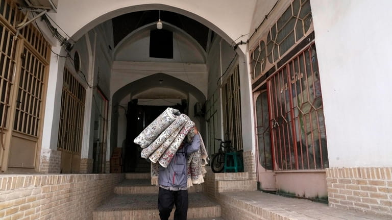 A worker carries carpets at the traditional bazaar of the...