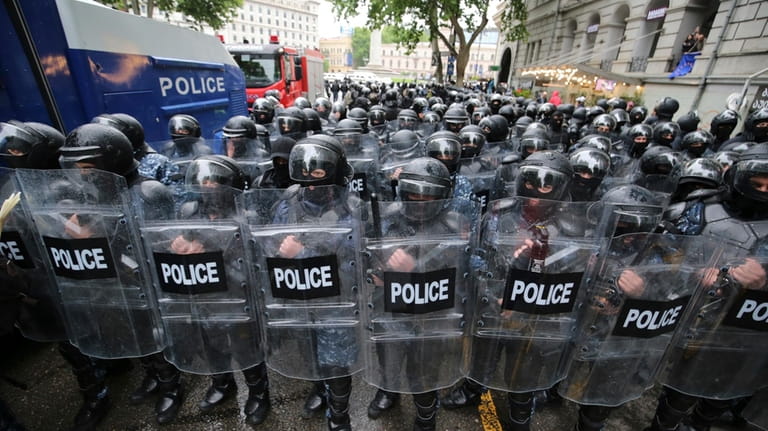 Riot police block a street to prevent demonstrators during an...