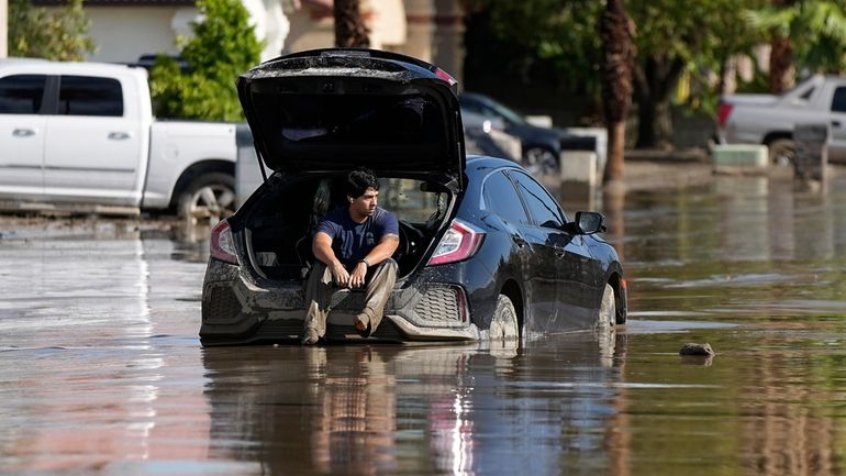 Dorian Padilla sits in his car as he waits for...