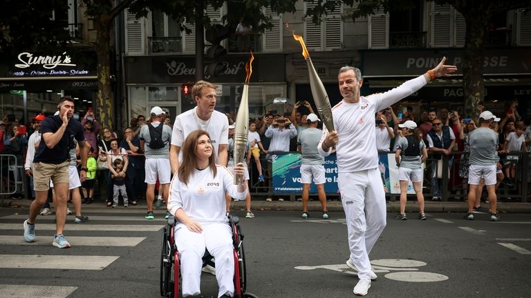 Press agency photographer Christina Assi, left, holds the Olympic torch...