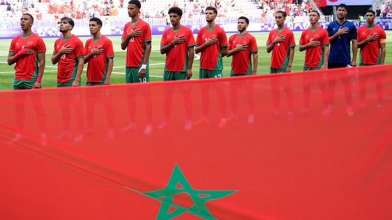 Morocco athletes listen to their national anthem prior to a...