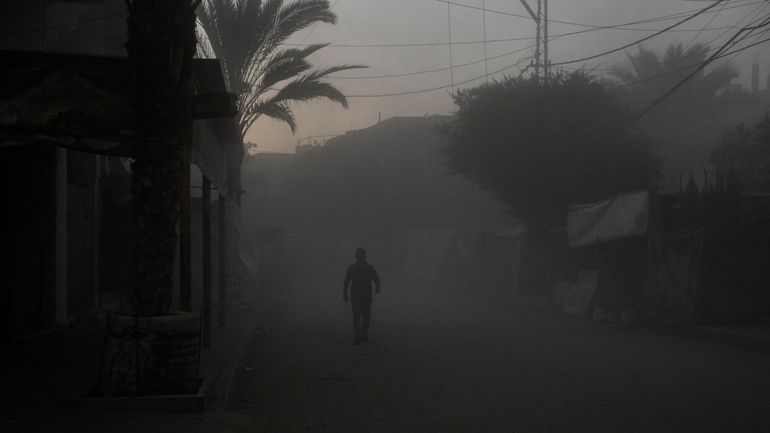 A Palestinian walks on a smoke-filled street after an Israeli...