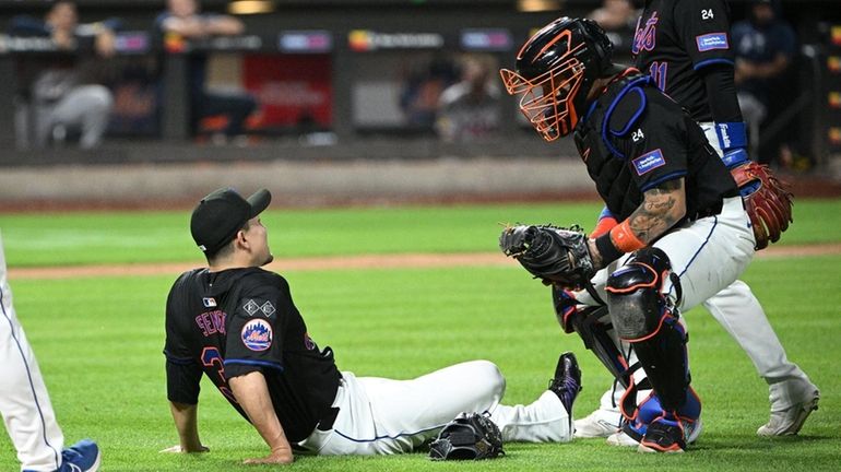 Mets catcher Francisco Alvarez, Jose Iglesias and a trainer check...