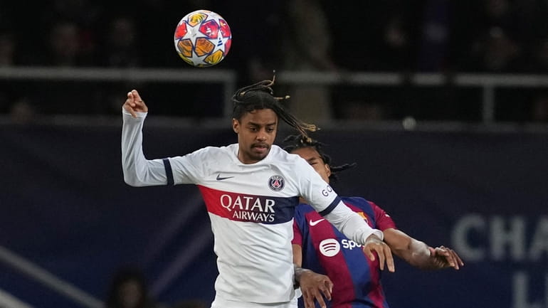 PSG's Bradley Barcola, left, jumps for the ball with Barcelona's...