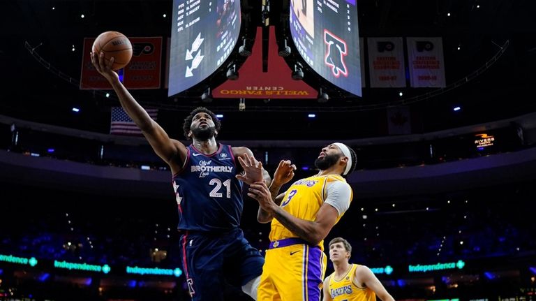 Philadelphia 76ers' Joel Embiid, left, goes up for a shot...